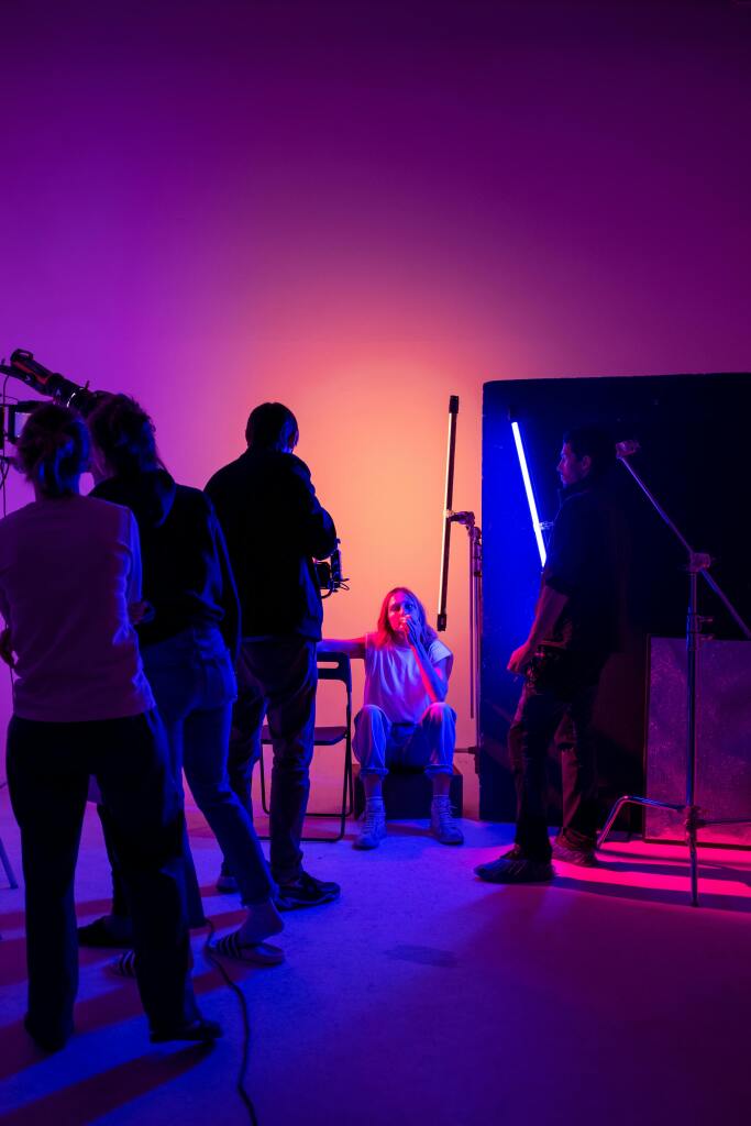 Artistic photoshoot session with neon lighting, capturing a model in a creative studio environment.